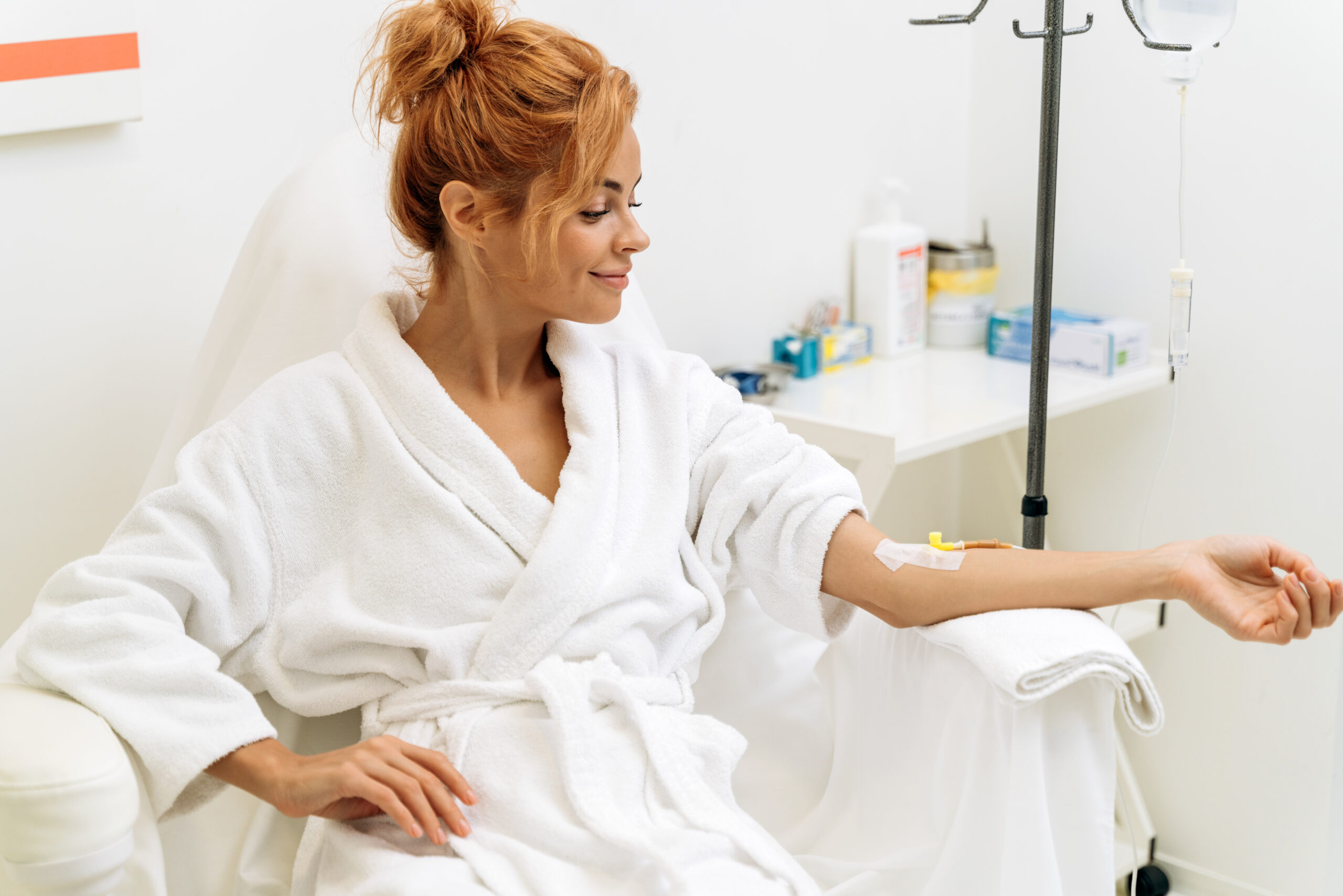 Portrait of mindful woman sitting in armchair and closed eyes while receiving IV infusion with vitamins. Cosmetology and medicine concept